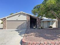 Charming single-story home featuring stone accents, a two-car garage, and mature landscaping in a well-kept yard at 1441 Bronco Rd, Boulder City, NV 89005
