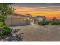 Stunning single-story home featuring multiple garages, brick driveway, and beautiful desert landscaping at 2997 Via Meridiana, Henderson, NV 89052