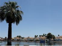 Waterfront view of resort-style homes, lush landscaping, and a serene lake at 3150 Soft Breezes Dr # 1167, Las Vegas, NV 89128
