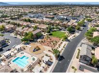 Expansive aerial view of a community featuring a pool, playground, and green spaces amidst neatly arranged homes at 4351 Hera Temple Ave, North Las Vegas, NV 89031