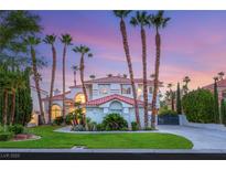 Elegant two-story home featuring lush landscaping, tall palms, and a red tile roof against a beautiful twilight sky at 1905 Iron Ridge Dr, Las Vegas, NV 89117