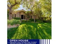 Beautiful stone home with manicured lawn and mature trees offering shade and curb appeal at 33 Promontory Ridge Dr, Las Vegas, NV 89135