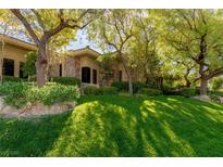 Beautiful home exterior with mature trees, lush landscaping, and stone accents creating a serene and inviting ambiance at 33 Promontory Ridge Dr, Las Vegas, NV 89135