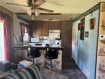 A view of a kitchen with dark countertops, bar seating, and a ceiling fan with light at 1507 Elizabeth Ave # 1, Las Vegas, NV 89119