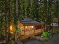 Charming cabin with a covered porch, surrounded by lush greenery and mature trees at 4581 Aspen Ave, Mount Charleston, NV 89124