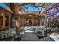 Idyllic backyard oasis featuring mature trees, a charming bridge, and a tranquil pond at 15 Emerald Dunes Cir, Henderson, NV 89052