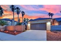 Spacious two-car garage and paved driveway under a vibrant sunset, surrounded by palm trees at 5509 Rose Thicket St, Las Vegas, NV 89130