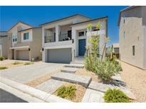 Charming two-story home featuring a balcony, gray-tone stucco, a paver driveway, and minimalist desert landscaping at 10429 Rose Palisade St, Las Vegas, NV 89141