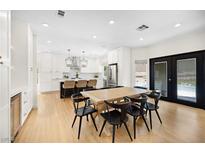Bright, open kitchen and dining area featuring white cabinets, stainless steel appliances, and a large island at 10645 Redwood Grove Ave, Las Vegas, NV 89144