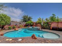 Beautiful backyard pool featuring a central rock waterfall and surrounding brick patio at 10656 Hyde Corner Ave, Las Vegas, NV 89166