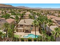 Expansive aerial view of a home with a private pool surrounded by lush landscaping and palm trees at 11056 Kilkerran Ct, Las Vegas, NV 89141