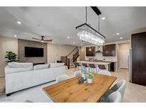 Open concept living room, dining area, and kitchen with modern light fixtures and stainless steel appliances at 11402 Ethereal Landing Ave, Las Vegas, NV 89138