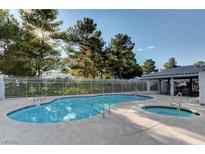A community pool and spa are surrounded by a fence, trees, and a covered patio at 2132 Chertsey Dr # B, Las Vegas, NV 89108