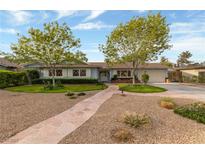 Charming single-story home with a landscaped front yard, stone walkway, and mature trees at 2400 Llewellyn Dr, Las Vegas, NV 89102