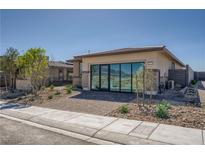 Modern single-story home featuring desert landscaping, brick drive, and sliding glass doors at 9357 Aria Ridge Ave, Las Vegas, NV 89143