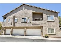 Condominium complex featuring stucco exterior, multiple garages, and a balcony against a clear blue sky at 2000 Gravel Hill St # 203, Las Vegas, NV 89117