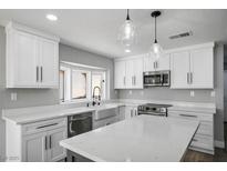 Modern kitchen featuring white cabinets, quartz countertops, stainless appliances, and stylish pendant lighting at 7060 W Rome Blvd, Las Vegas, NV 89131