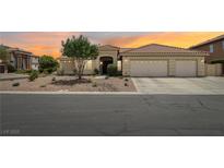 Beautiful single-story home featuring a three-car garage, desert landscaping, and a tile roof at sunset at 9410 Stone Castle Way, Las Vegas, NV 89123