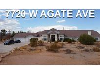 Expansive single-story home with desert landscaping, multiple-car garage, and grand entrance, bathed in natural light at 7720 W Agate Ave, Las Vegas, NV 89113