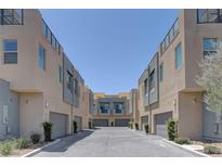 Modern townhomes feature neutral stucco exteriors, garages, and a paved driveway under a clear blue sky at 11377 Gravitation Dr, Las Vegas, NV 89135