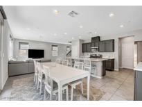 Open-concept living room and kitchen with modern gray cabinets, a large island, and a white dining set at 15 Santo Mio Ct, Henderson, NV 89011