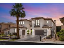 Elegant two-story home featuring a tile roof, a palm tree, and a driveway leading to attached garages at 11453 Glowing Sunset Ln, Las Vegas, NV 89135
