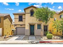 Two-story home featuring tan stucco, a tile roof, a well-manicured lawn, and an attached garage at 11894 Snow Bank St, Las Vegas, NV 89183