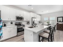 Bright kitchen features white cabinets, stainless steel appliances, and a spacious island with seating at 288 Whitney Crest St, Henderson, NV 89015