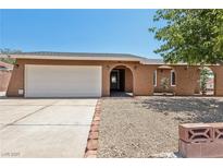 Charming single-story home featuring a two-car garage, an arched entryway, and desert landscaping at 667 Del Prado Dr, Boulder City, NV 89005