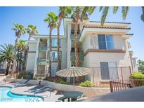 Condo building exterior with private balconies and a community pool, all surrounded by lush palm trees at 7155 S Durango Dr # 205, Las Vegas, NV 89113