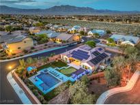 Stunning aerial view of a home featuring a pool, putting green, solar panels, and mountain views at 10319 Larkmead Ave, Las Vegas, NV 89149