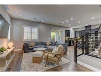 Spacious living room features a plush sectional sofa, wooden floors, and natural light from the large window at 10360 Pescado Ln, Las Vegas, NV 89135