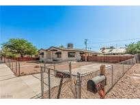 Charming single-story home with fenced yard, offering a blend of security and curb appeal under a clear blue sky at 1832 Merze Ave, Henderson, NV 89011