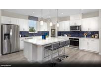 Modern kitchen features stainless steel appliances, a large island with seating, and stylish blue backsplash at 314 S Parawan St # Lot 13, Henderson, NV 89015