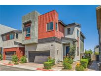 Modern two-story home with a gray stucco exterior and red siding accent, complemented by a well-maintained front yard at 3194 Lumassina Way, Henderson, NV 89044