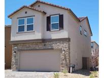 Two-story home featuring stone accents and a beige-colored stucco exterior, showcasing modern design and curb appeal at 7375 Davenbury St, Las Vegas, NV 89113