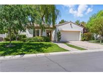 Charming single-story home with lush green lawn, mature trees, and a brick driveway to a two-car garage at 11775 Woodbrook Ct, Las Vegas, NV 89141
