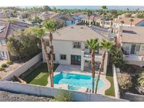 Beautiful backyard pool with putting green, palm trees, covered patio, and a white stucco home at 1811 Country Meadows Dr, Henderson, NV 89012