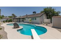Inviting in-ground pool with diving board and rock feature complemented by a covered patio, perfect for outdoor relaxation at 1852 E Viking Rd, Las Vegas, NV 89169
