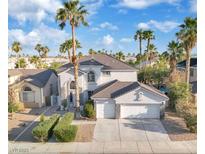 Charming two-story home featuring a two-car garage, desert landscaping, and mature palm trees at 6909 Fruit Flower Ave, Las Vegas, NV 89130