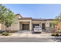 Inviting single-story home with dual garages, desert landscaping, and a charming entryway under a clear blue sky at 7472 Garnet Moon St, North Las Vegas, NV 89084