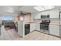 Well-lit kitchen features white cabinets and stainless steel appliances overlooking the living area at 8070 W Russell Rd # 1023, Las Vegas, NV 89113
