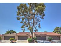 Charming single-story townhome with a tile roof, well-manicured front yard, and a mature tree in the front at 1857 Arbol Verde Way, Las Vegas, NV 89119