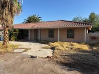 Single-story home with a red tile roof, beige stucco exterior, and front yard with desert landscaping at 4928 E Philadelphia Ave, Las Vegas, NV 89104