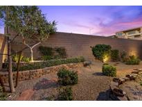 Backyard featuring a stone bench, gravel, and lush green landscaping against a block wall at 816 Stannard Ct, Henderson, NV 89052