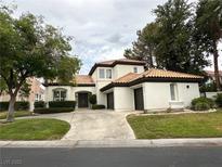 Charming single-story home featuring a lush front lawn, tile roof and three-car garage at 8761 Rainbow Ridge Dr, Las Vegas, NV 89117