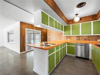 Retro kitchen features wood paneling, green cabinets, orange countertops and stainless steel appliances at 2245 Sombrero Dr, Las Vegas, NV 89169