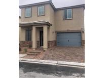 Two-story home with tan stucco, stone accents, a two-car garage, and a paver driveway and walkway at 5414 Enchanted Rose St, Las Vegas, NV 89148