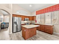 Well-lit kitchen with stainless steel refrigerator and kitchen island topped with granite countertops at 9733 Northern Dancer Dr, Las Vegas, NV 89117