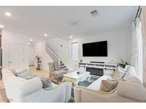 Bright living room features plush seating, modern entertainment center with fireplace, and staircase at 10347 Restless River St, Las Vegas, NV 89141